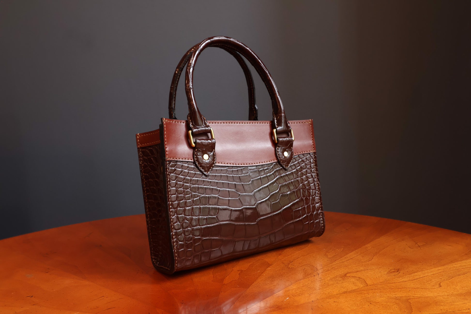 The Darlington handbag by Garrett Wayne - dark brown American alligator leather body with cognac leather trim and brass hardware, three-quarter view